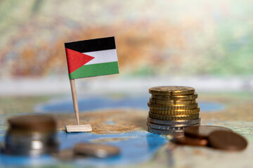 palestinian flag with stacked coins on a world map, symbolizing economy, financial system, and...
