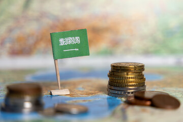 saudi arabia flag with stacked coins on map background, representing national economy, wealth,...