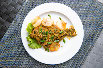 Rupchanda curry topping with green onion, tomato and lettuce leave served in plate isolated on grey...