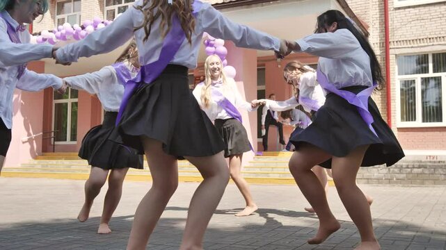 Graduates of the school twirl in a round dance holding hands.