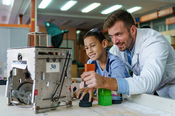 Engaged Mid Adult Tutor and Boy with Robot in Science Class