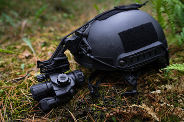  Ballistic helmet with night vision monocular lies on the ground.