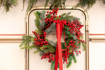 Christmas wreath made of holly berries and branch fir tied with a red bow hangs on door motor home....