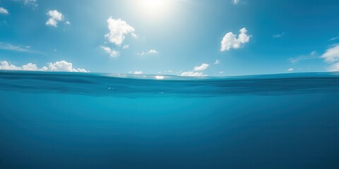 Obraz premium Blue ocean water surface with bright sunlight shining through the clouds, revealing the beautiful underwater world below, beautiful, water