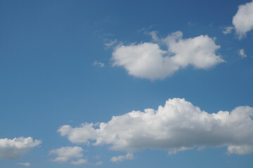 White fluffy clouds in the sky. Blue sky and cloud cover on a sunny summer day. Empty background, copy space