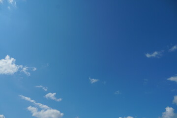 White fluffy clouds in the sky. Blue sky and cloud cover on a sunny summer day. Empty background, copy space