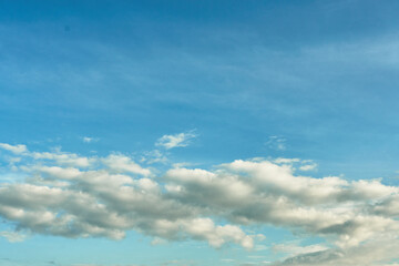 Fototapeta premium White fluffy clouds in the sky. Blue sky and cloud cover on a sunny summer day. Empty background, copy space