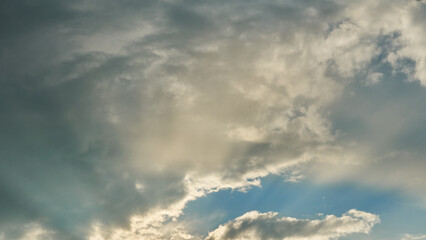 Fluffy orange clouds in a blue sky illuminated by the light of the setting sun. Pure nature, untouched by man. Climate change as a result of human activity.