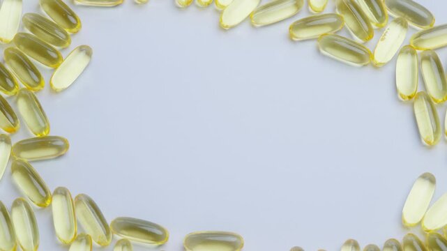 A close-up image of yellow omega-3 fish oil capsules arranged in a border on a white background. Ideal for health, wellness, and nutrition-themed concepts.