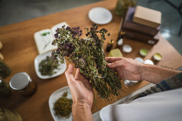 unknown man handle dried herbs on wooden table with herbal setup