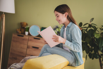 Obraz premium Charming young girl reading indoors, surrounded by comfort and inspiration in a cozy home setting