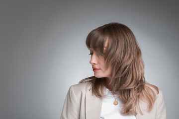 Attractive woman with stylish haircut on grey gradient background, space for text