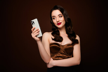 Photo of stunning rich girl wear fashionable clothes use gadget isolated on brown color background
