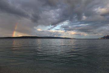 Rainbow in cloudy sky over sea on rainy day, Baska Voda, Croatia