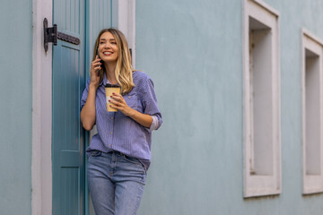 Fototapeta premium Young Woman Smiling While Talking on Phone with Coffee