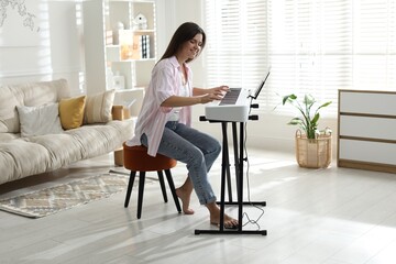 Smiling woman playing synthesizer at home. Electronic musical instrument