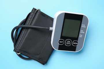 Blood pressure measuring device on light blue background, top view