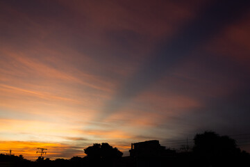 Sunset sky with clouds and silhouette of a city,