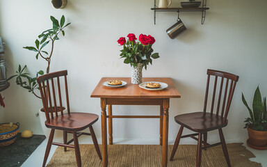 Fototapeta premium Dining table set for two with cookies and a bouquet in a cozy kitchen area