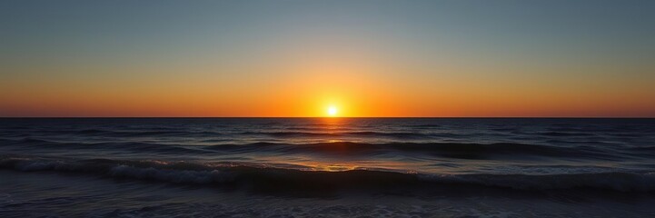 The setting sun casts a golden glow over the ocean as the day succumbs to night, light, waves, clouds