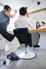 Obraz premium 美容室で鏡を見ながら髪の仕上がりを見る美容師と男性のお客さま こんな感じでいかがでしょうか？ 