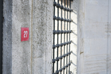 A Numbered Jail Cell Door Featuring Sturdy Metal Bars and a Concrete Wall