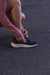 Close-up of woman tying her running shoe on asphalt