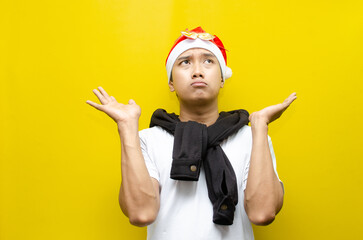 Thoughtful Young Asian Man in Santa Hat and Scarf Celebrating Christmas with a Sad Expression, Deep...