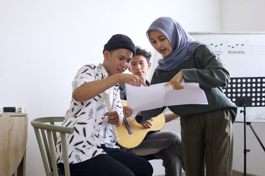 Happy Asian High School Students Learning Playing Musical Instrument And Singing In Class