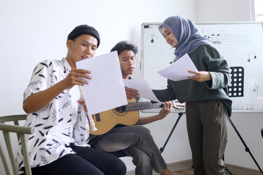 Happy Asian High School Students Learning Playing Musical Instrument And Singing In Class