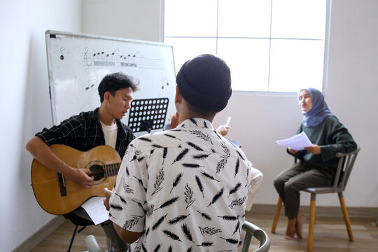 Happy Asian High School Students Learning Playing Musical Instrument And Singing In Class