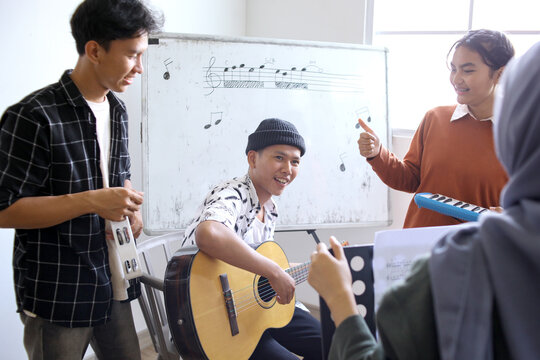 Happy Asian High School Students Learning Playing Musical Instrument And Singing In Class