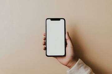 A hand holding a smartphone with a blank screen against a beige background.