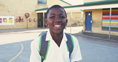Portrait close up of a young African schoolboy wearing his school uniform and schoolbag, looking to