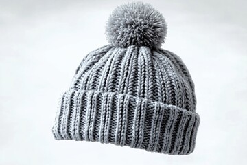 Cozy gray knitted beanie with a fluffy pom-pom, ideal for winter fashion, holiday gifts, or promotional materials. Perfect for seasonal campaigns and apparel designs.