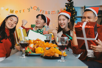 Group of young Asian man and women as friends having fun at a New Year's celebration, holding gift...