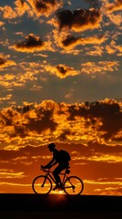 Obraz premium Cyclist silhouetted against the sunset, with room for text in the sky.