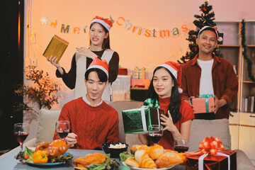 Group of young Asian man and women as friends having fun at a New Year's celebration, holding gift...