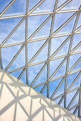 Glass roof of the mall inside view with part of white concrete wall and lightning protection system outside. Vertical shot.