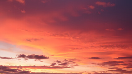 Fototapeta premium A serene dusk sky featuring layers of orange and deep purple with scattered cloud textures 
