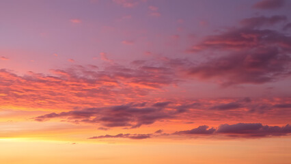 Fototapeta premium A serene dusk sky featuring layers of orange and deep purple with scattered cloud textures 