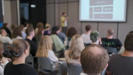Diverse group of people attending a seminar, listening attentively to a presentation. The atmosphere is focused and educational, highlighting the importance of knowledge sharing and learning.