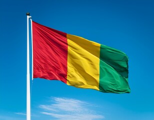 Guinea flag waving in the wind against a blue sky background