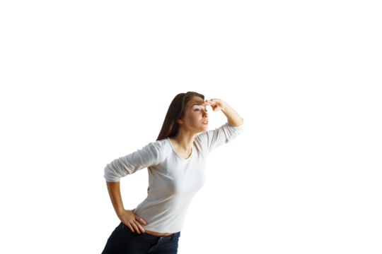 Woman gazing into the distance with hand shielding eyes, wearing white shirt and jeans, isolated on clean white background, concept of searching