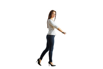 A woman in a white top and dark jeans holding a microphone, standing casually. Simple white background. Concept of speaking, presentation, or communication