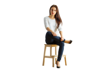 Woman wearing casual white sweater and jeans sitting on a wooden stool, isolated on a white background. Concept of casual style and confidence