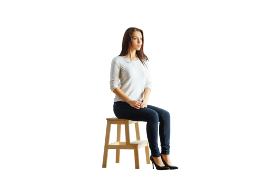 A young woman sitting on a wooden stool wearing a casual outfit, isolated on a white background. Concept of simplicity, minimalism, and lifestyle