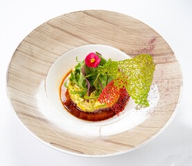 Salad with Sauce, Greens, and Edible Flower on a Plate Against a White Background