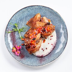 Fried Quail with Greens and White Sauce on a Plate Against a White Background