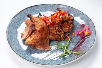 Fried Quail with Greens and White Sauce on a Plate Against a White Background
